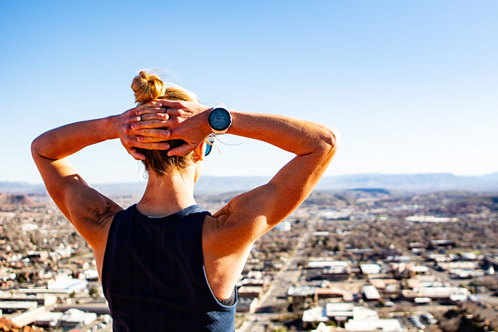 A woman at the top of a hill wearing a Suunto watch